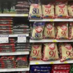The image depicts a grocery store aisle stocked with bags of rice and beans, including brands like Tío Pelón. Sales offers are prominently displayed, highlighting the essentials for many households.