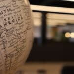 A close-up of a globe focused on South America, with countries like Brazil, Peru, and Bolivia clearly visible. The blurred background with warm lighting creates a soft bokeh effect, adding depth and a sense of exploration and travel.