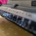A shallow-focus close-up of a vintage mechanical scale resting on a patterned tablecloth, with worn measurement markings fading into soft blur. The image evokes nostalgia, precision, and everyday craftsmanship found in traditional kitchens and old household tools.